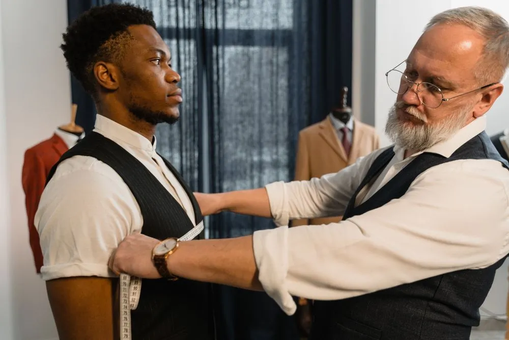 Un tailleur prend les mesures d’un homme pour ajuster son costume